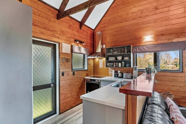 Une cuisine moderne avec des murs en bois, un four encastré et une grande fenêtre.