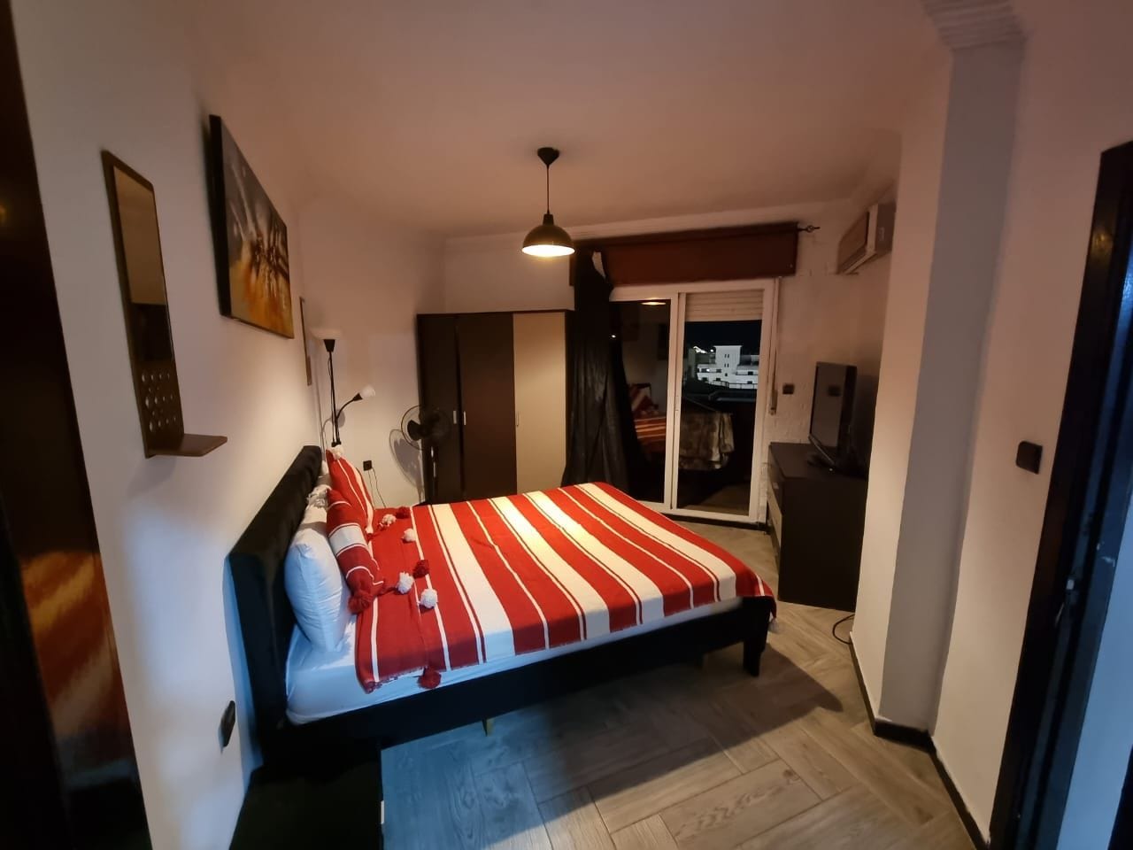 Une chambre à coucher comprenant un lit, une armoire, un bureau et un téléviseur.