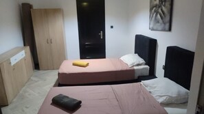 Ein Zimmer mit zwei Betten, einem Kleiderschrank und einer Tür.