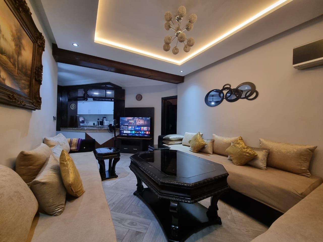 Ein modernes Wohnzimmer mit einer Sofagarnitur, einem Couchtisch und einem Fernseher im Hintergrund.