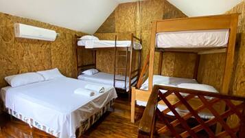 A room with bunk beds, a wooden floor, and an air conditioning unit.