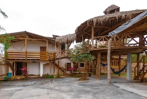 A traditional wooden structure with a thatched roof, a staircase, and a hammock. - Hostal Tortuga Dorada (Puerto López)