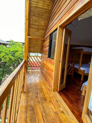 Una cabaña de madera con balcón, puerta de madera y una cama.