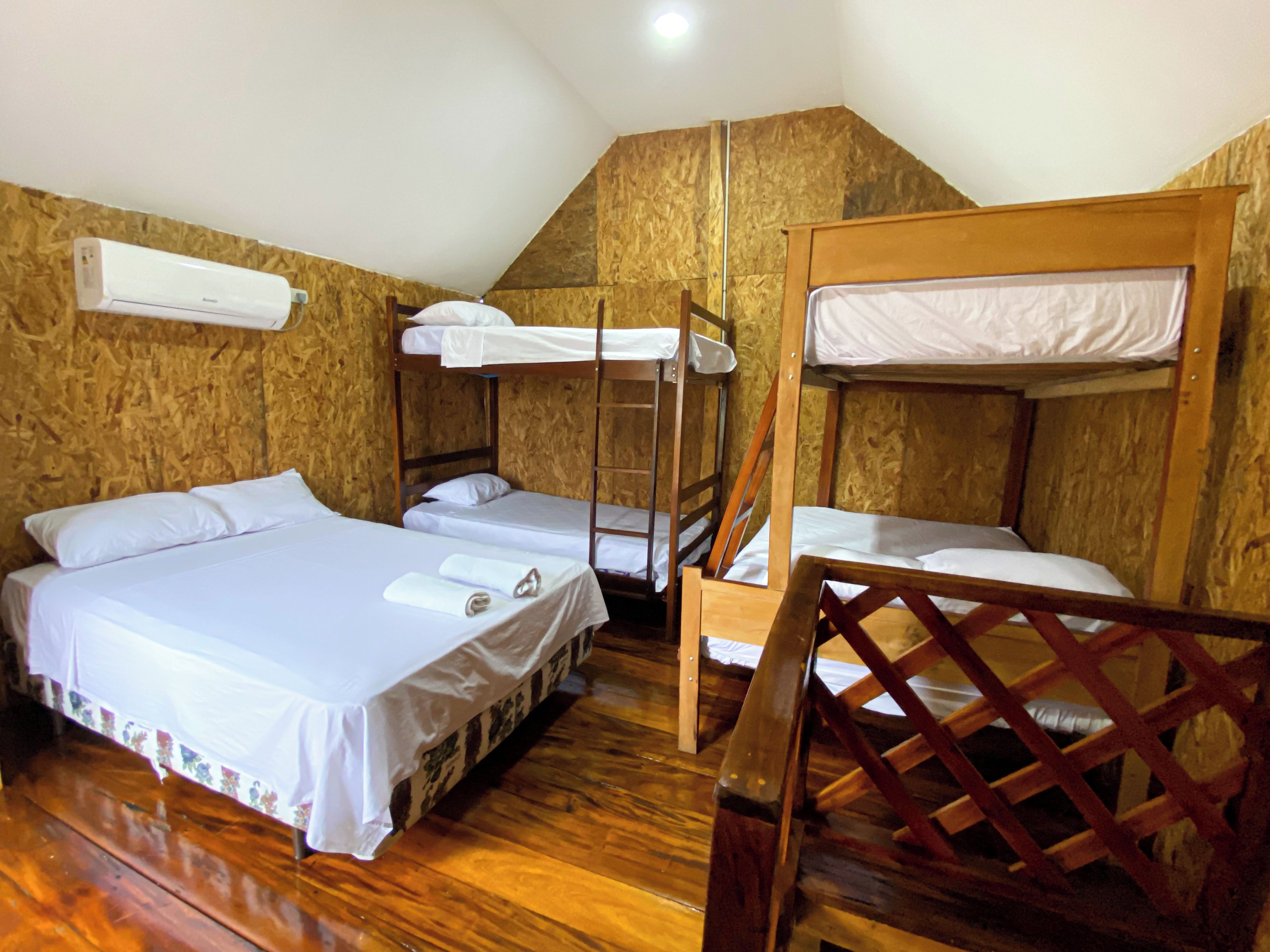 Una habitación con literas, piso de madera y pared blanca.