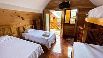 A cabin with two single beds and a bunk bed, wooden walls, a television, and a balcony.