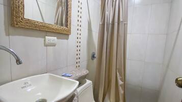 Un baño con lavamanos, inodoro y cortina de ducha.
