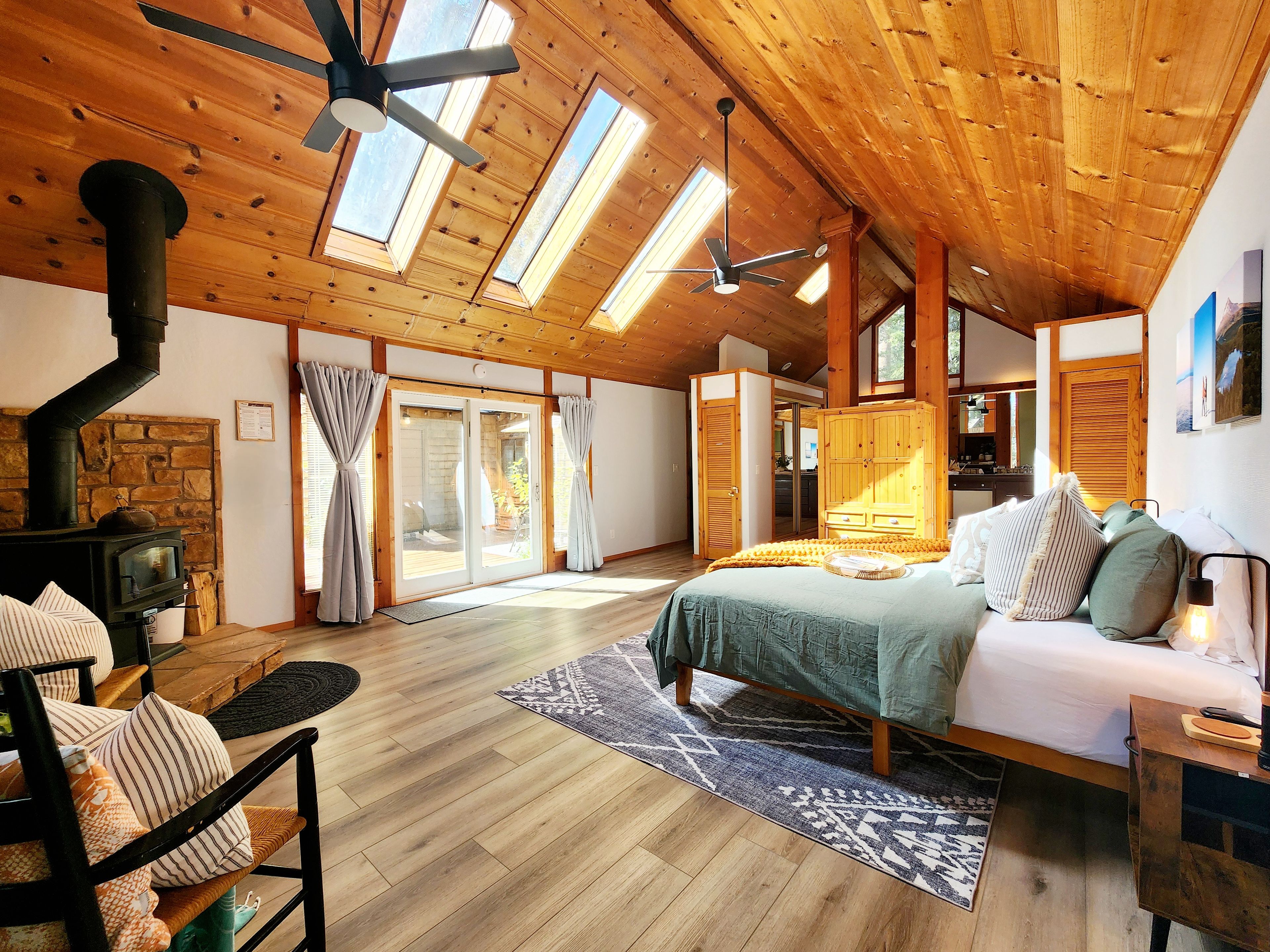 Een ruime kamer met een groot bed, een houten plafond en een stenen open haard.