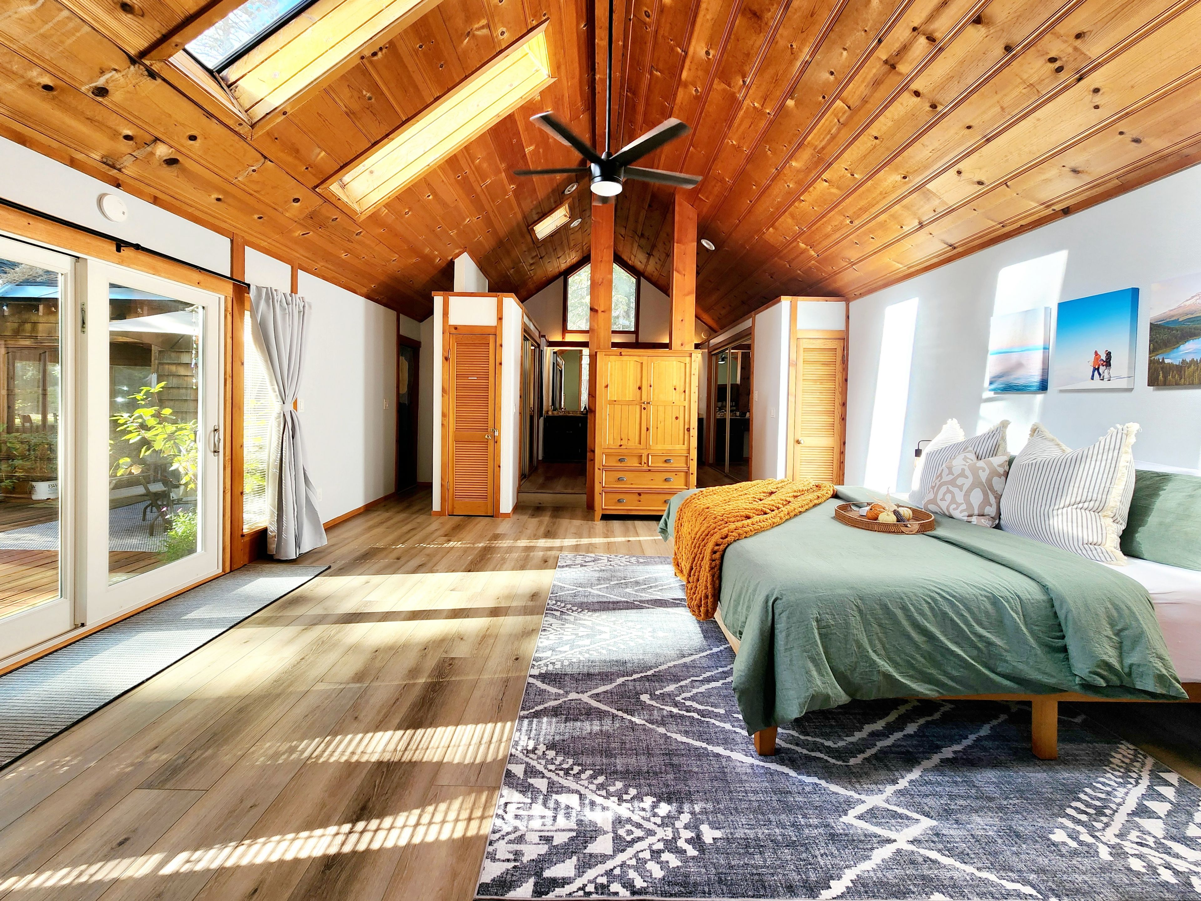A bedroom with a bed, a ceiling fan, and a view of the outdoors.