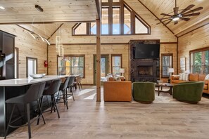 A spacious wooden interior with a dining area, sofas, and a fireplace. - NEW Smoky Mountain Swim-Inn Private Pool, Arcade in Pigeon Forge Dog Friendly (Pigeon Forge)
