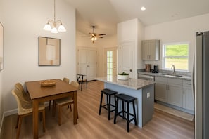 A spacious kitchen with a dining area, wooden flooring, and a ceiling fan.
