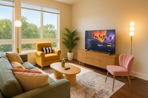 A modern living room with a sofa, armchair, coffee table, and a television on a wooden cabinet. - Modern Alexandria 1BR | Pool, Gym & Shops (Alexandria)