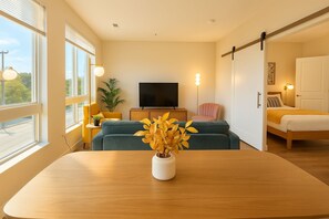 A modern living room with a sofa, a television, and a dining table with a vase of flowers.
