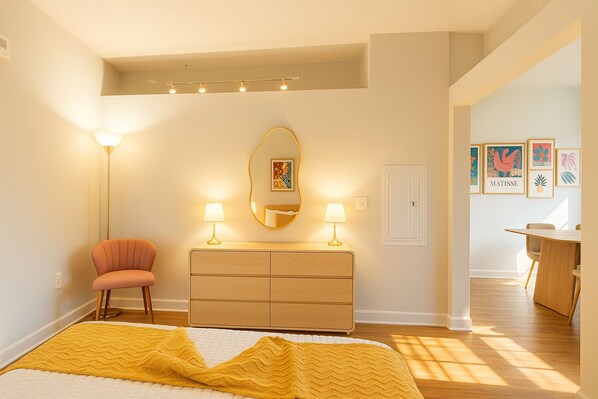 A bedroom with a bed, a dresser, a chair, a mirror, and a desk with a chair. - Modern Alexandria 1BR | Pool, Gym & Shops (Alexandria)