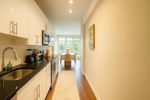 A modern kitchen with a black countertop, stainless steel appliances, and a dining area with a view.