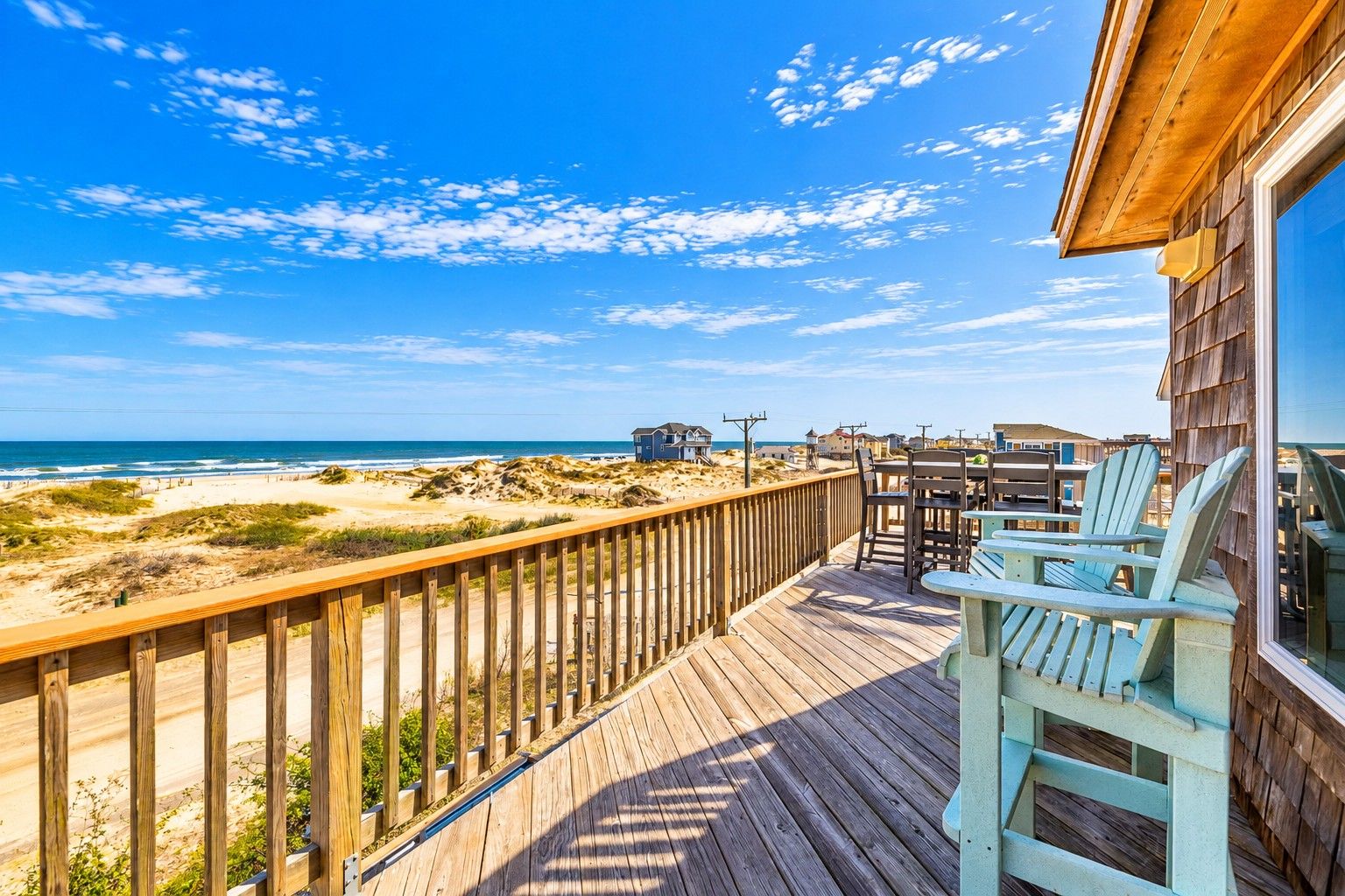 A wooden deck with a view of the beach and ocean.