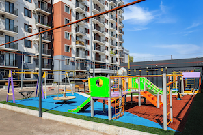 A playground with various play structures, surrounded by a building with multiple balconies and air conditioning units. - Apartments Chakar 369 Tashkent (Tashkent)