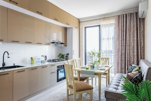 A modern kitchen with a dining area, featuring a built-in oven, a sink, and a dining table set with chairs. - Apartments Chakar 369 Tashkent (Tashkent)