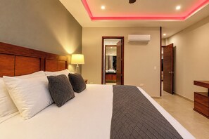 A hotel room with a large bed, a wooden headboard, a bedside lamp, a wardrobe, and an air conditioning unit. - Villa Almarez | Private Luxury Retreat (Tulum)