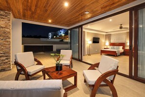 Habitación de hotel moderna con balcón, cama y zona de estar con sillas y una mesa.