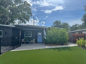 A residential property with a paved driveway, a blue door, and a fenced yard. - Furnished 5BR/3BA Home in Bayshore Beautiful — 30-Day Minimum (Tampa)