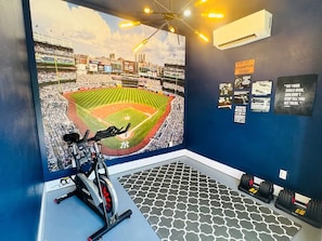 A gym with a large mural of a baseball stadium, exercise equipment, and motivational posters on the walls. - Furnished 5BR/3BA Home in Bayshore Beautiful — 30-Day Minimum (Tampa)