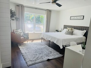 A bedroom with a bed, a desk, a chair, a window, and a ceiling fan. - Furnished 5BR/3BA Home in Bayshore Beautiful — 30-Day Minimum (Tampa)