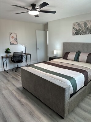 A bedroom with a bed, a desk, a chair, a ceiling fan, and a wall art piece. - Huge Modern 4Bdr home-The Xperience #2 (Houston)