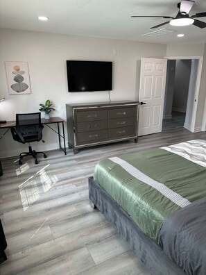 A bedroom with a bed, a dresser, a desk with a chair, a television, and a ceiling fan. - Huge Modern 4Bdr home-The Xperience #2 (Houston)