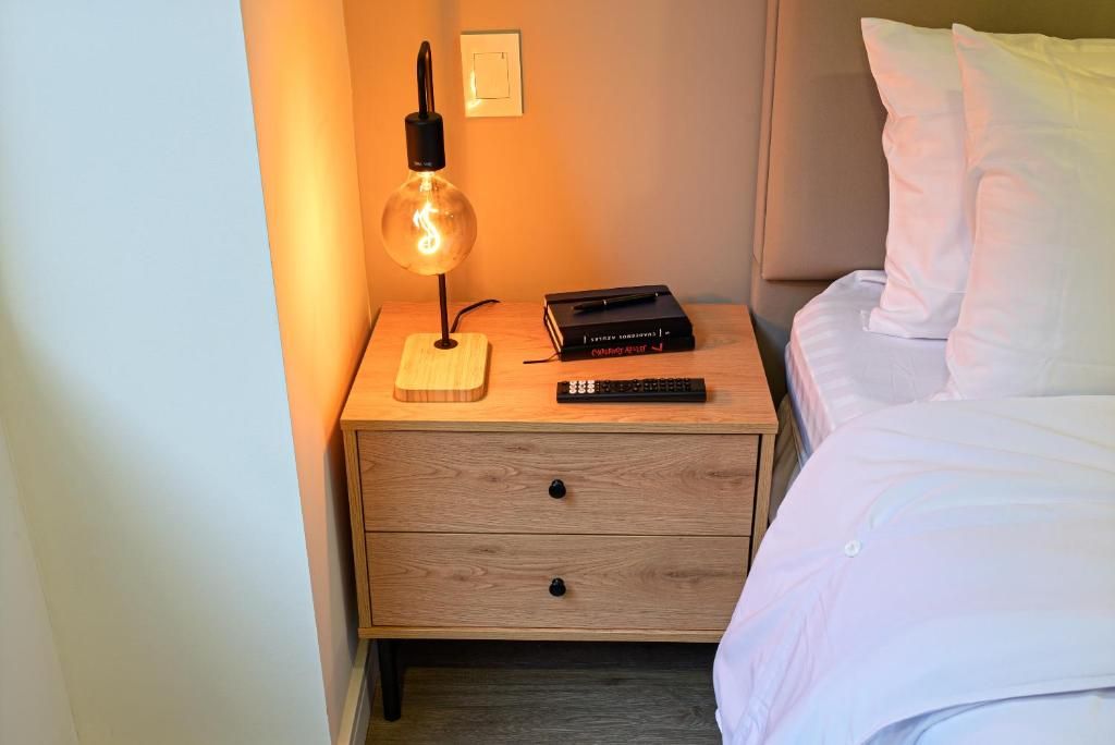 A neatly made bed with white linens, a bedside table with a lamp, a book, and a keyboard.