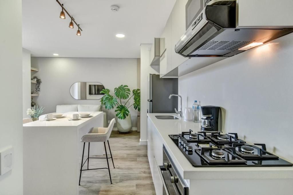 A modern kitchen with a central island, a gas stove, and a built-in oven.