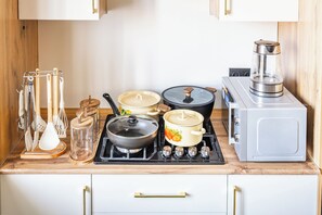A kitchen with a stove, pots, a kettle, and a coffee maker. - Apartments Nukus avenue Tashkent (Tashkent)
