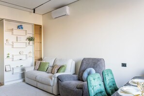 A modern living room with a sofa, armchairs, and a dining table set for a meal. - Apartments Nukus avenue Tashkent (Tashkent)