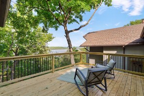 A wooden deck with a railing, two chairs, and a view of a lake. - Spacious and luxurious home on Table Rock Lake (Shell Knob)