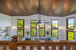 A room with a wooden ceiling, multiple windows with views of greenery, a ceiling fan, and a wooden railing. - Spacious and luxurious home on Table Rock Lake (Shell Knob)