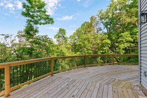 A wooden deck with a railing, surrounded by trees. - Spacious and luxurious home on Table Rock Lake (Shell Knob)