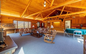 A log cabin interior with a fireplace, seating area, and a view of the outdoors. - The Lodge at Wapiti Valley Ranch- ideally located between Cody and Yellowstone (Cody)