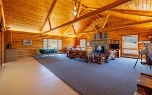 A log cabin interior with a fireplace, a dining area, and a large window. - The Lodge at Wapiti Valley Ranch- ideally located between Cody and Yellowstone (Cody)