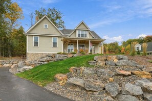 A two-story house with a stone retaining wall and a grassy front yard. - Luxury Owl’s Nest Retreat Golf & Resort (Campton)