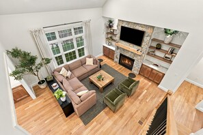 A spacious living room with a large sofa, a coffee table, and a fireplace. - Luxury Owl’s Nest Retreat Golf & Resort (Campton)