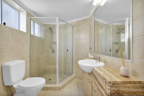A bathroom with a glass-enclosed shower, a white toilet, a sink, and a mirror. - Studio Apartment - Poolside Tower - No Balcony (Kings Beach)
