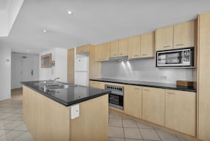Une cuisine moderne avec des meubles en bois, une hotte en acier inoxydable et un four encastré.