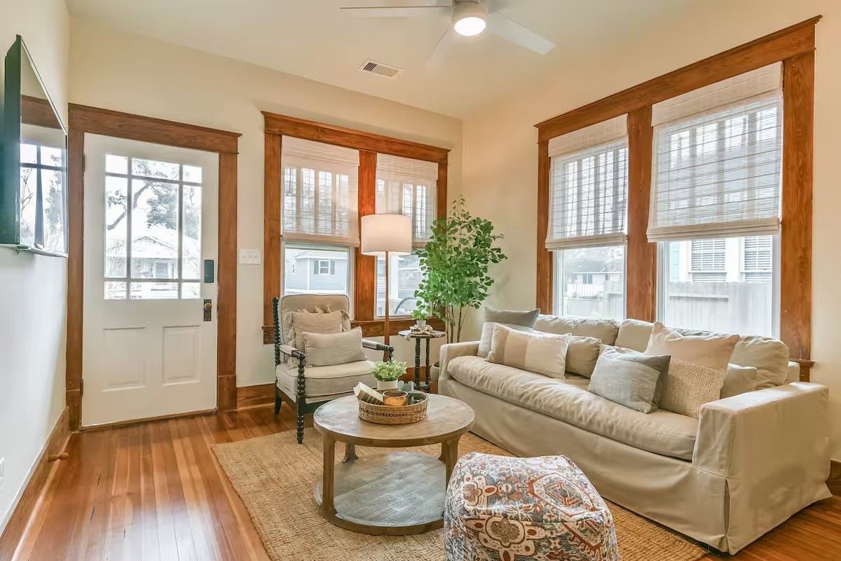 A living room with a sofa, armchair, coffee table, and a potted plant.