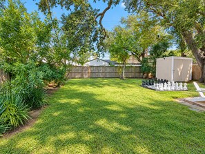 A backyard with a chessboard set up, a shed, and a wooden fence. - The Mustard House - Featured on Restoring Galveston (Galveston)