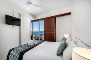 A hotel room with a bed, a TV, a window with a view, and a ceiling fan. - 2 Bedroom Rooftop Poolside (Kings Beach)