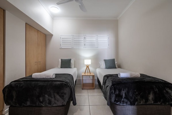 A hotel room with two beds, a wooden wardrobe, a ceiling fan, and a window with shutters. - 2 Bedroom Rooftop Poolside (Kings Beach)