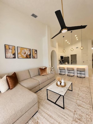 Una sala de estar moderna con un sofá modular, una mesa de centro y un ventilador de techo.