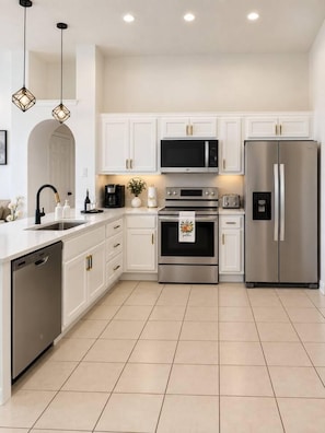 Una cocina moderna con armarios blancos, electrodomésticos de acero inoxidable y lavavajillas.