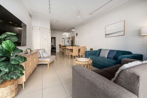 Una sala de estar moderna con un sofá, una zona de comedor y una cocina al fondo.