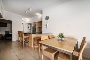 Una cocina moderna con una isla central, sillas de madera y una mesa de comedor con una planta en maceta.