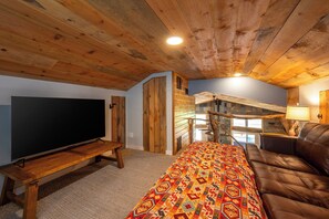 A cozy living room with a flat-screen TV, a sofa, a patterned rug, and a staircase leading to an upper level. - Waterfall Retreat at Peppermint Falls (Springville)